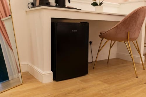 Piccola cucina con frigorifero nero nell'appartamento Mas Collection a Bari, con scrivania in legno e sedia cognac