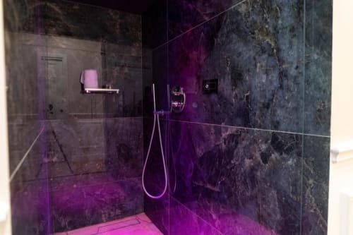 Bagno moderno con marmi scuri e illuminazione ambientale viola nell'appartamento Mas Collection, Bari