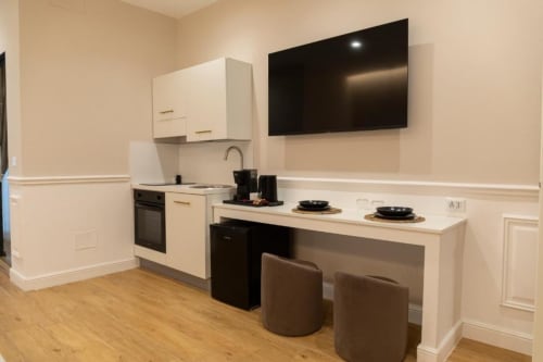Cucina moderna nella Mas Collection Bari con mobili bianchi, elettrodomestici neri, isola centrale e TV a parete