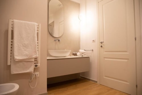 Bagno moderno nella Pink Room di Mas Collection a Bari, con lavabo a bacinella, scaldasalviette e eleganti finiture bianche