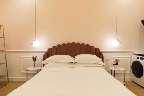 Camera da letto moderna della Pink Room di Mas Collection a Bari, con testiera in terracotta, biancheria color crema, lampade a sospensione e comodini