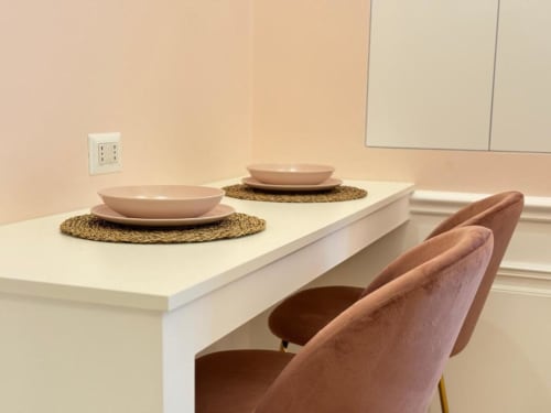 Sala da pranzo moderna nella Pink Room di Mas Collection Bari con tavolo bianco, mise en place e sedie imbottite