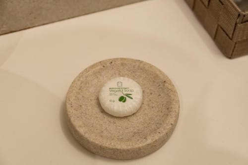 Sapone vegetale con estratto di oliva su piatto di pietra rotondo nel bagno dell'appartamento Mas Collection Bari
