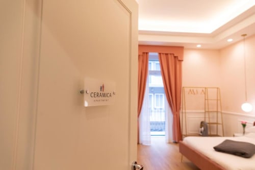 Camera da letto nell'appartamento Ceramica a Bari con arredi moderni, tende arancioni, accesso al balcone e arredamento minimalista