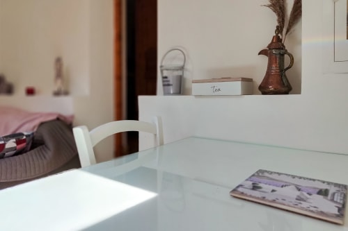 Table de salle à manger avec magazine au gîte Domaine Bellavigne, étagère avec boîte à thé et décoration en cuivre