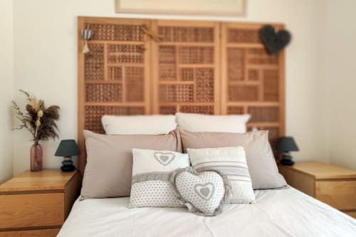 Chambre douillette du gîte les Cyprès avec tête de lit en bois, literie blanche et coussins cœur décoratifs au Domaine