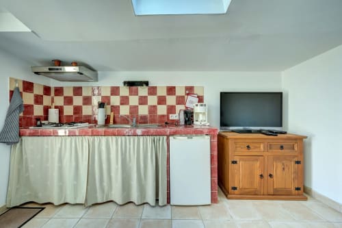 Kitchenette de cottage avec carrelage à damier rouge, réfrigérateur blanc, meuble en bois avec télévision et puits de lumière au Domaine