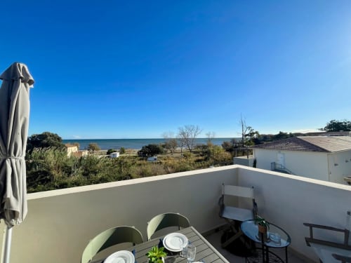 Terrazza con vista mare della Résidence Marina di Bravone, tavolo da pranzo e costa mediterranea a Linguizzetta