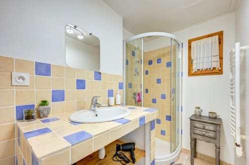 Salle de bain moderne avec carrelage crème et bleu, lavabo blanc et douche à l'italienne dans un gîte de Forcalquier