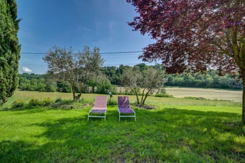 Deux fauteuils lounge violets sur pelouse verte avec oliviers et vue sur la campagne au Domaine Bellavigne Gîtes et Spa