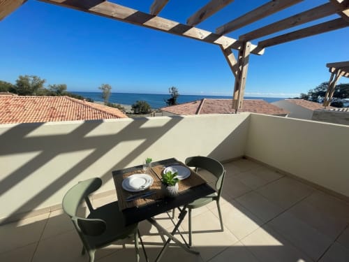 Terrazza con vista mare a Marina di Bravone con tavolo da pranzo, pergolato in legno e vista sul Mediterraneo