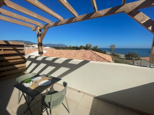 Terrazza con vista mare della Résidence Marina di Bravone, Corsica, con pergolato in legno, tavolo da pranzo e panorama sul mare