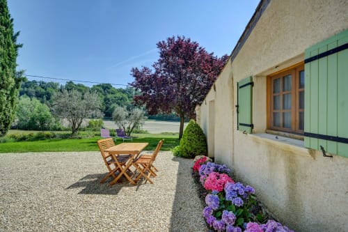 Terrasse du gîte Domaine Bellavigne à Forcalquier : table en bois, hortensias et volets verts