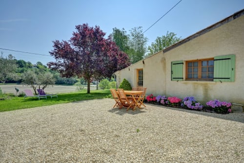 Jardin et terrasse du gîte les Cyprès avec mobilier de jardin en bois, fleurs colorées et vue sur la campagne de Forcalquier