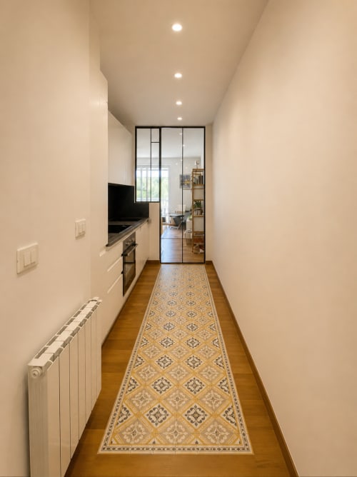 Cuisine en galère moderne avec éclairage encastré, murs blancs, sol en bois et couloir à motifs géométriques chez Riviera Home