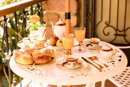 Elegante servizio da tè all'aperto presso l'Hôtel Villa Martini di Ajaccio con pasticcini, fiori e accenti dorati