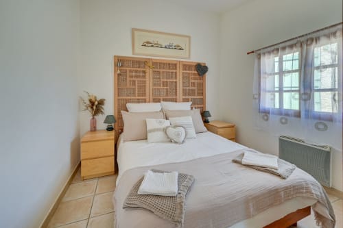 Chambre accueillante au Domaine Bellavigne Gîtes et Spa à Forcalquier avec lits en bois, literie neutre et tête de lit en rotin.