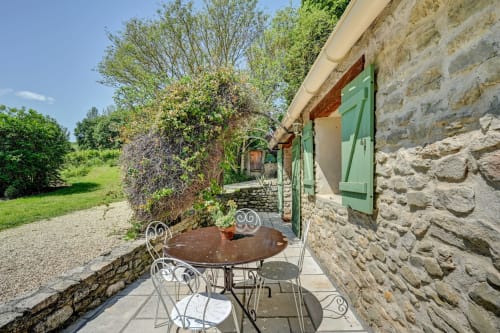 Salon de jardin sur la terrasse de Domaine Bellavigne Gîtes et Spa à Forcalquier, avec bâtisse en pierre et volets verts