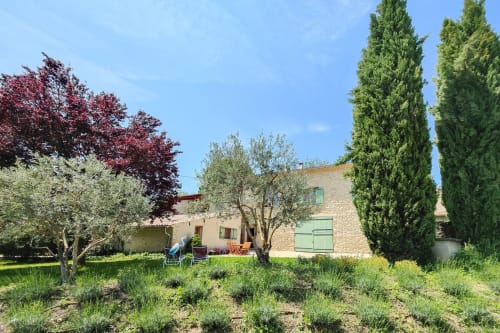 Jardins champêtres du Domaine Bellavigne avec bâtisses en pierre, oliviers et cyprès à Forcalquier, France
