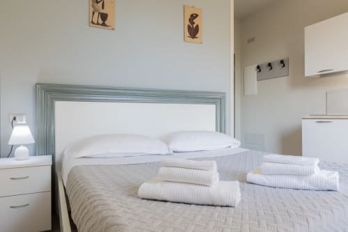 Camera da letto pulita dell'Hotel Prince Garda a Solarolo con asciugamani piegati sul letto e testata turchese