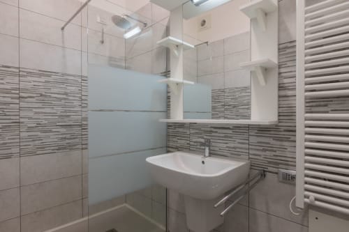 Bagno moderno dell'hotel Prince Garda a Solarolo con piastrelle a righe, doccia in cristallo, lavabo bianco e riscaldamento