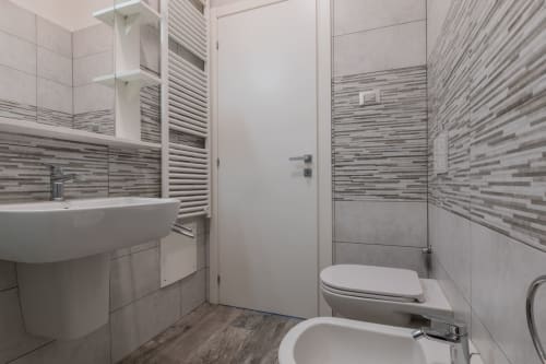 Bagno moderno dell'Hotel Prince Garda a Solarolo con piastrelle decorate, lavabo bianco, WC e box doccia