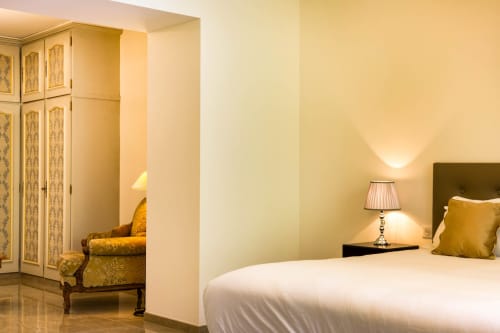 Camera elegante all'Hôtel Villa Martini di Ajaccio con letto bianco, poltrona damascata dorata e illuminazione calda