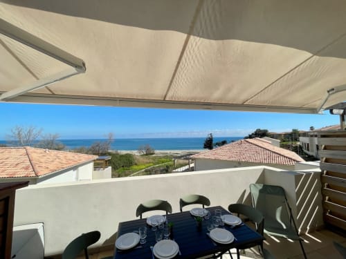 Terrasse panoramique avec vue sur mer à la Résidence Marina di Bravone, aménagée pour dîner, pergola rétractable et vue sur la côte corse