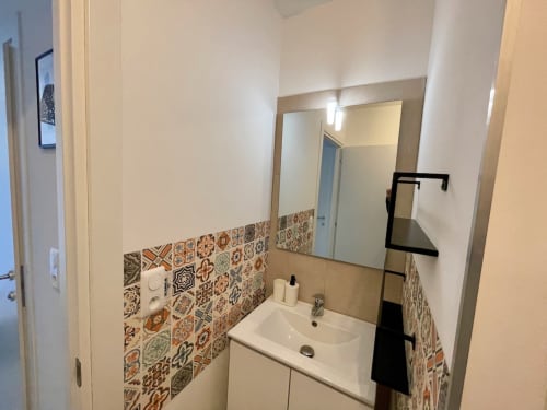 Salle de bain moderne à la Résidence Marina di Bravone avec carrelage à motifs, lavabo blanc et miroir à Linguizzetta