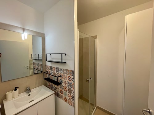 Salle de bain moderne à la Résidence Marina di Bravone avec lavabo, miroir, carrelage à motifs et douche