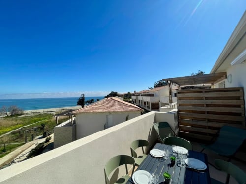 Balcon de l'appartement Marina di Bravone avec vue mer, table à manger et paysage côtier à Linguizzetta