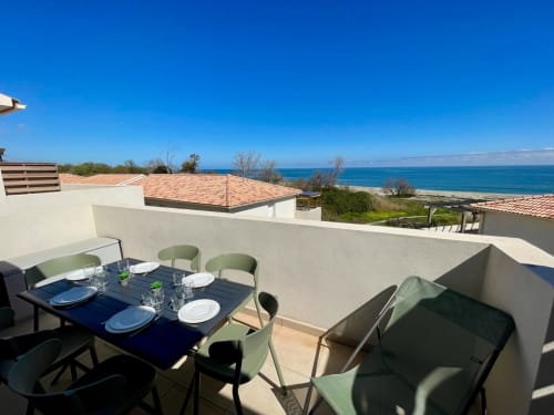 Terrasse sur le toit de la Résidence Marina di Bravone avec table à manger, vue sur la mer et littoral méditerranéen