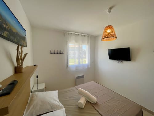 Chambre moderne à la Résidence Marina di Bravone, Linguizzetta avec lit, télévision, bureau en bois et lampe suspendue