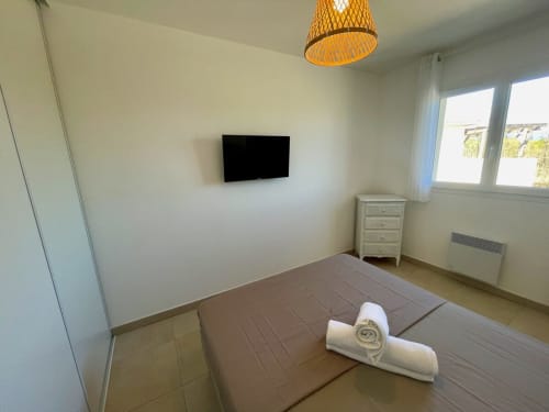 Camera moderna presso Résidence Marina di Bravone con TV a parete, asciugamani arrotolati, comò e finestre con vista sul mare