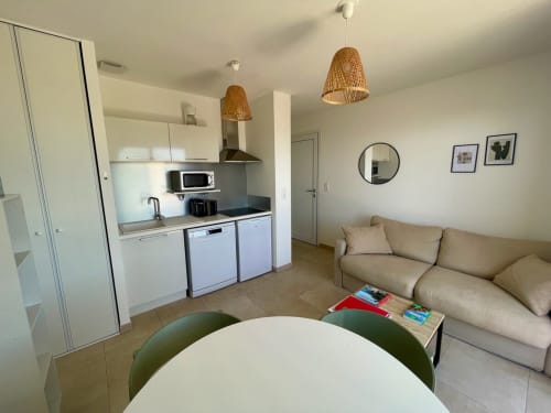 Appartamento moderno a Résidence Marina di Bravone con cucina a vista, divano beige e arredamento costiero a Linguizzetta