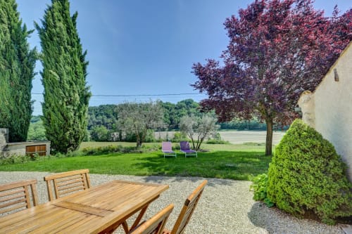 Terrasse de jardin extérieure au Domaine Bellavigne avec mobilier de salle à manger en bois, chaises longues et vue panoramique sur Forcalquier