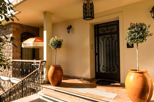 Elegante ingresso dell'Hôtel Villa Martini ad Ajaccio con vasi in terracotta, porta nera ornamentale e cortile in stile mediterraneo