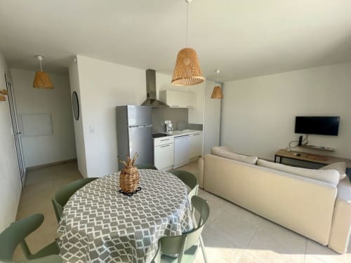 Open-plan T3 apartment at Résidence Marina di Bravone with dining area, kitchen, living room and woven pendant lights