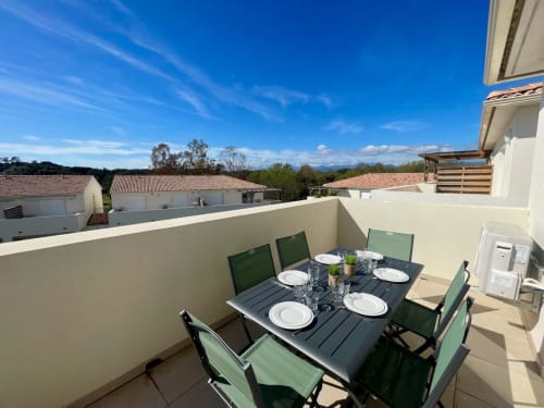 Rooftop terrace at Résidence Marina di Bravone with dining table, green chairs, mountain views