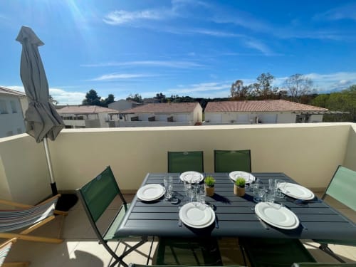 Rooftop terrace at Marina di Bravone with set dining table, Corsican countryside views, and umbrella