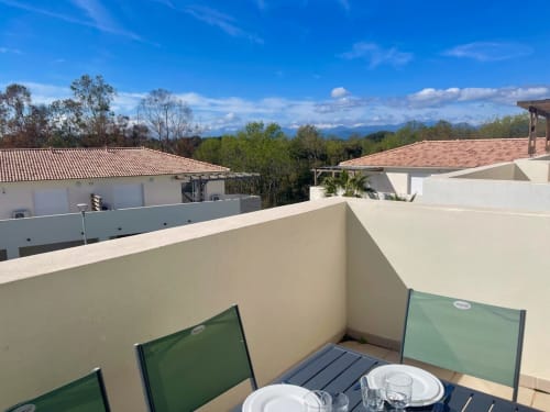Terrace view at Marina di Bravone, Linguizzetta, with dining area, white walls, and mountain vista beyond neighboring villas