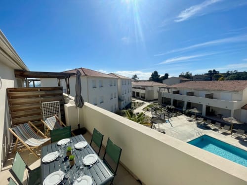 Rooftop terrace at Marina di Bravone with dining table, loungers, and pool view overlooking resort courtyard in Linguizzetta