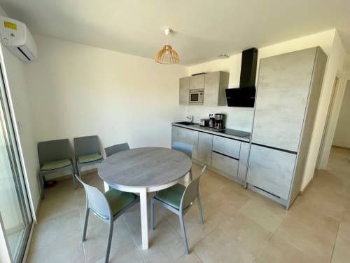 Moderna zona cucina-soggiorno dell'appartamento T3 a Résidence Marina di Bravone, Linguizzetta con tavolo rotondo e arredamento contemporaneo