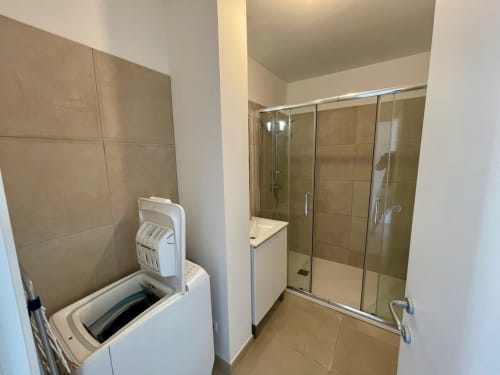 Moderno bagno della Résidence Marina di Bravone a Linguizzetta con doccia, lavatrice e finiture in piastrelle neutre