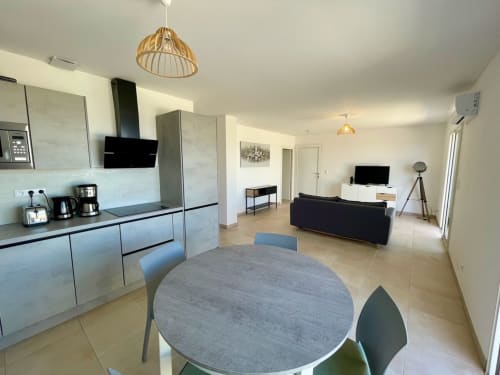Moderno appartamento open-plan presso la Résidence Marina di Bravone con cucina, tavolo da pranzo e zona living con divano nero
