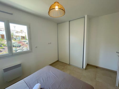 Camera moderna presso Résidence Marina di Bravone con letto, armadio a muro, lampada in legno e vista sul giardino