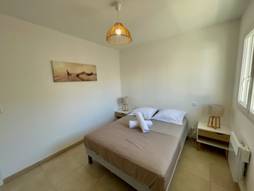 Camera moderna a Résidence Marina di Bravone con letto matrimoniale, lampada a sospensione in legno e vista mare a Linguizzetta