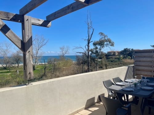 Terrazza sul mare della Résidence Marina di Bravone con vista oceano, zona pranzo, pergolato in legno e vegetazione costiera