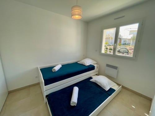 Due letti a castello con materassi blu scuro in una luminosa camera da letto della Résidence Marina di Bravone, Linguizzetta