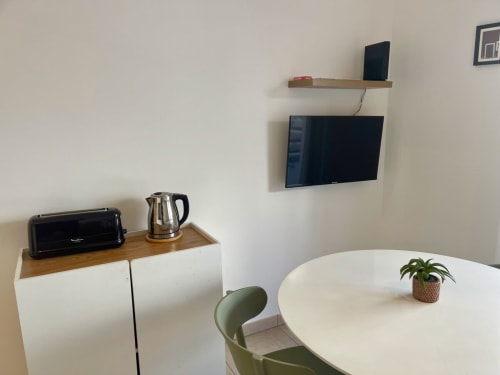 Chambre moderne à la Résidence Marina di Bravone avec télévision murale, meuble en bois avec bouilloire, table ronde blanche